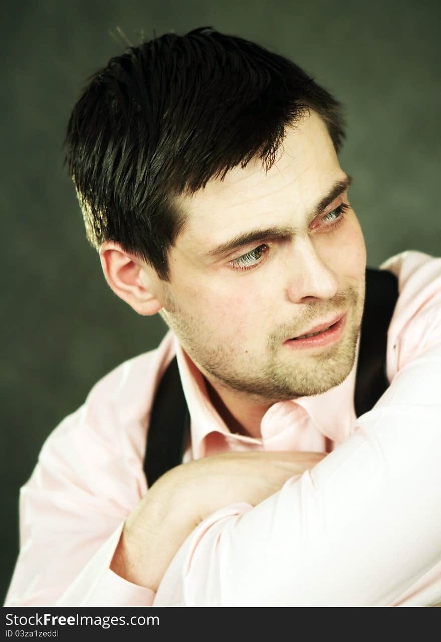 Thoughtful young man in pink shirt on gray background