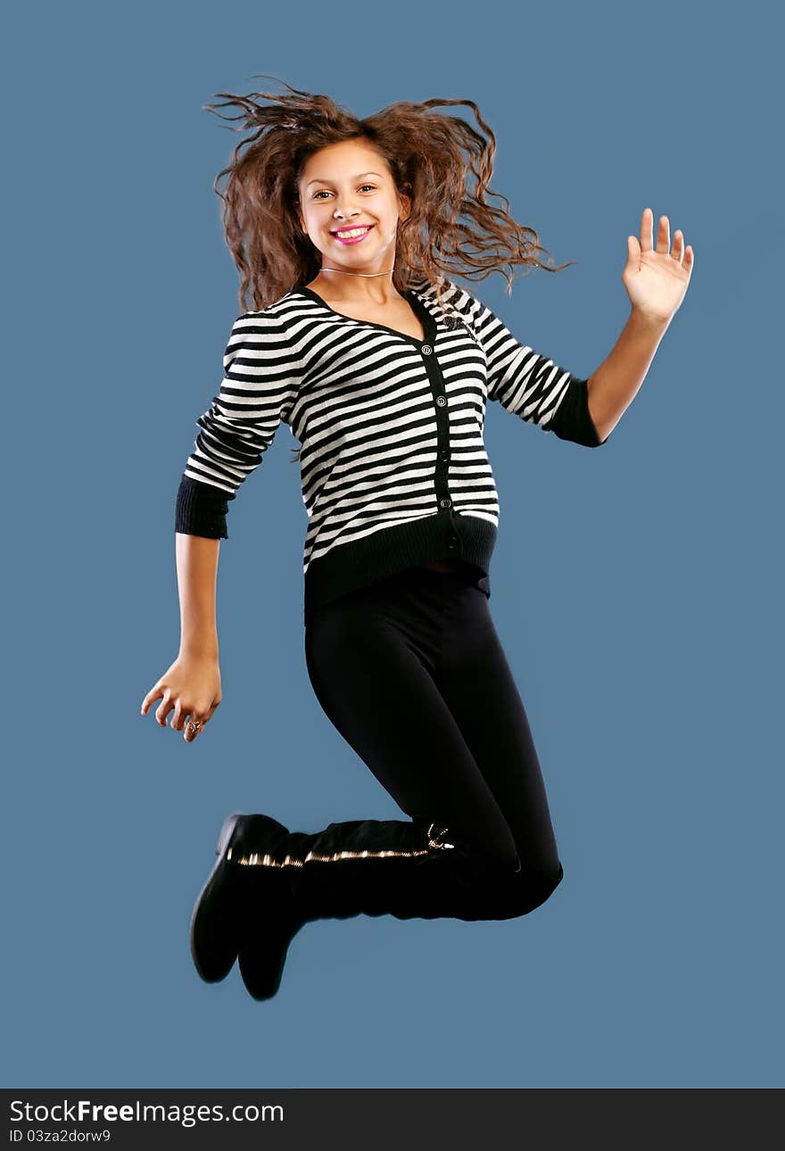 Young beautiful happy woman jumping against blue background