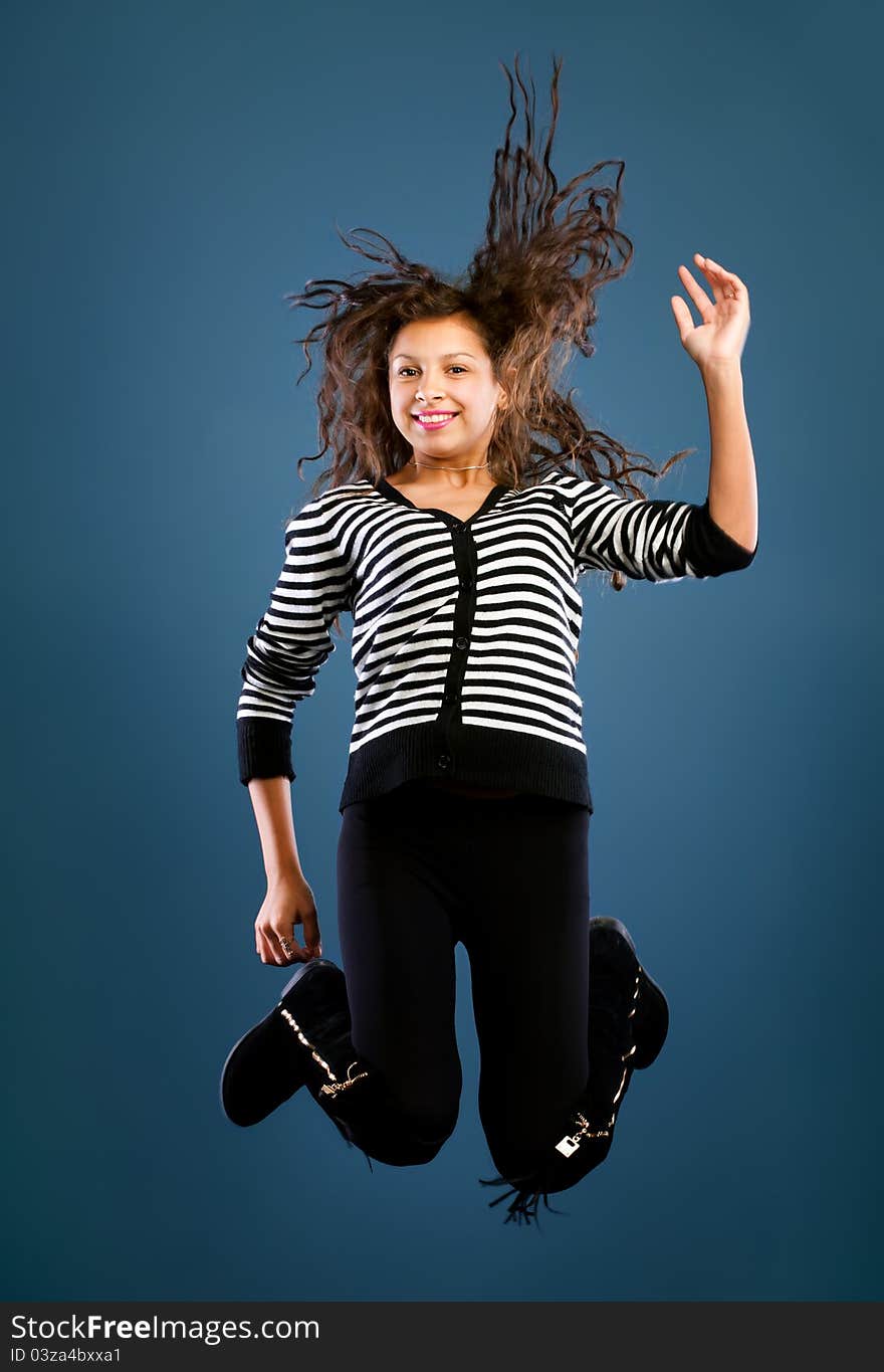 Young beautiful happy woman jumping against blue background