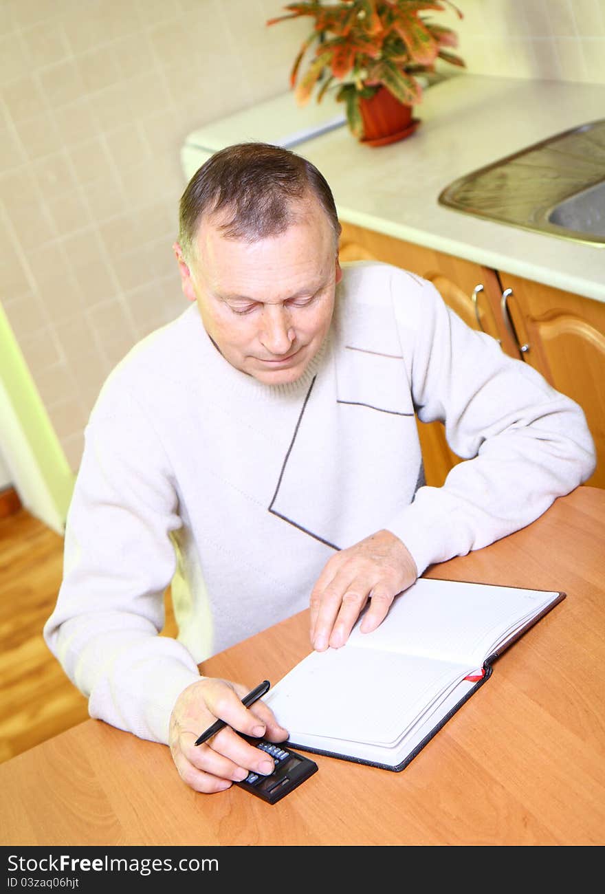 Older man concentrating on job, using calculator at home. Older man concentrating on job, using calculator at home