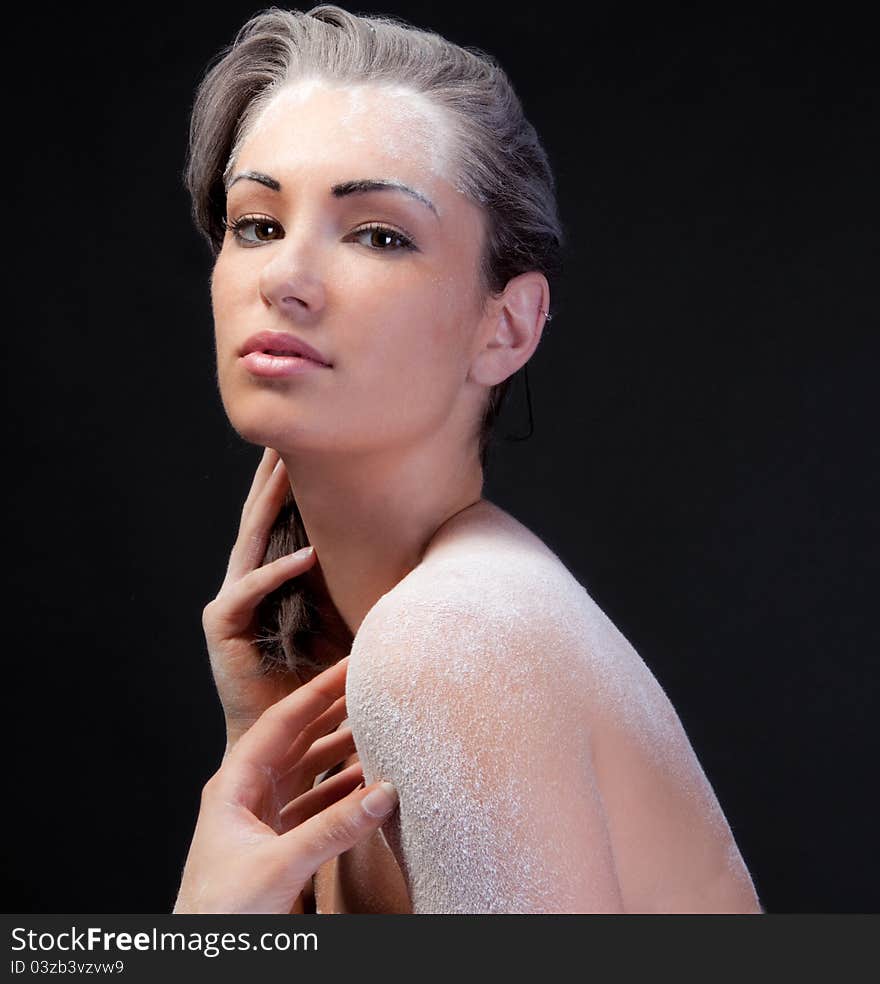 An interesting portrait of a pretty young woman with her hair, forehead, back, and shoulders sprinkled with white powder. An interesting portrait of a pretty young woman with her hair, forehead, back, and shoulders sprinkled with white powder