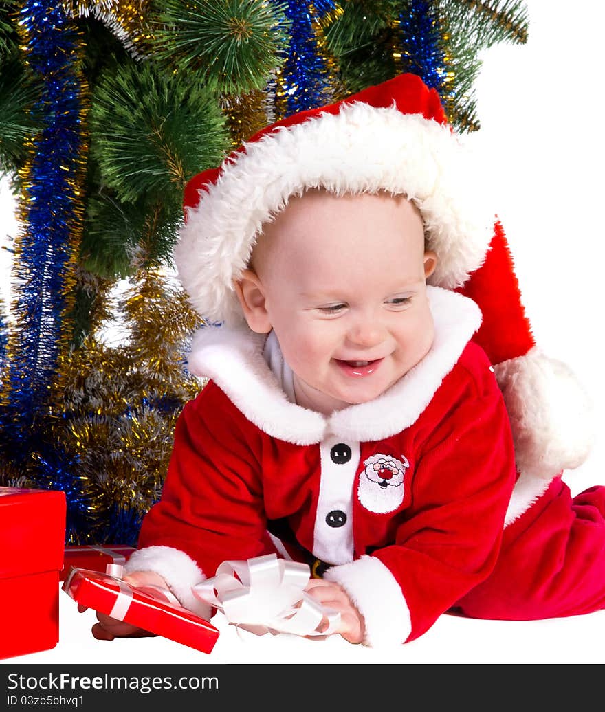 Little baby boy wearing Santa's costume sitting and holding a box with christmas 
presents