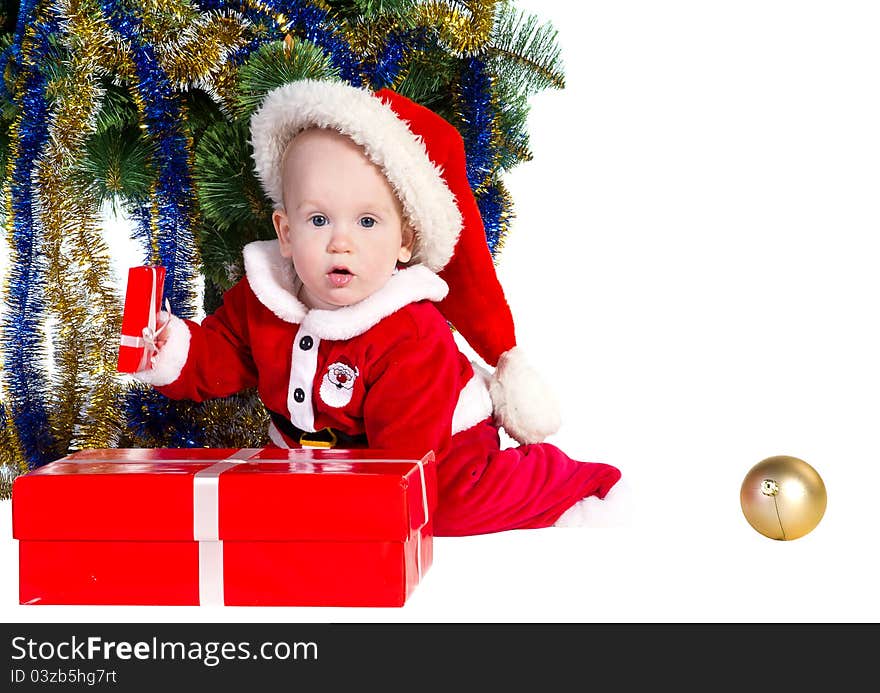 Little baby boy wearing Santa's costume sitting and holding a box with christmas presents