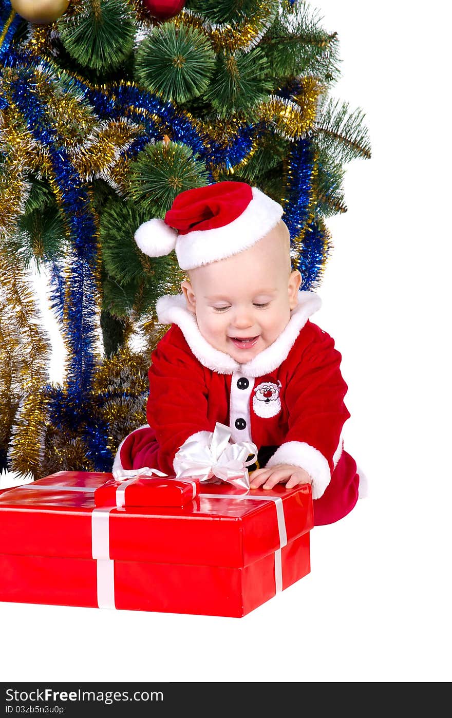 Little baby boy wearing Santa's costume sitting and holding a box with christmas 
presents