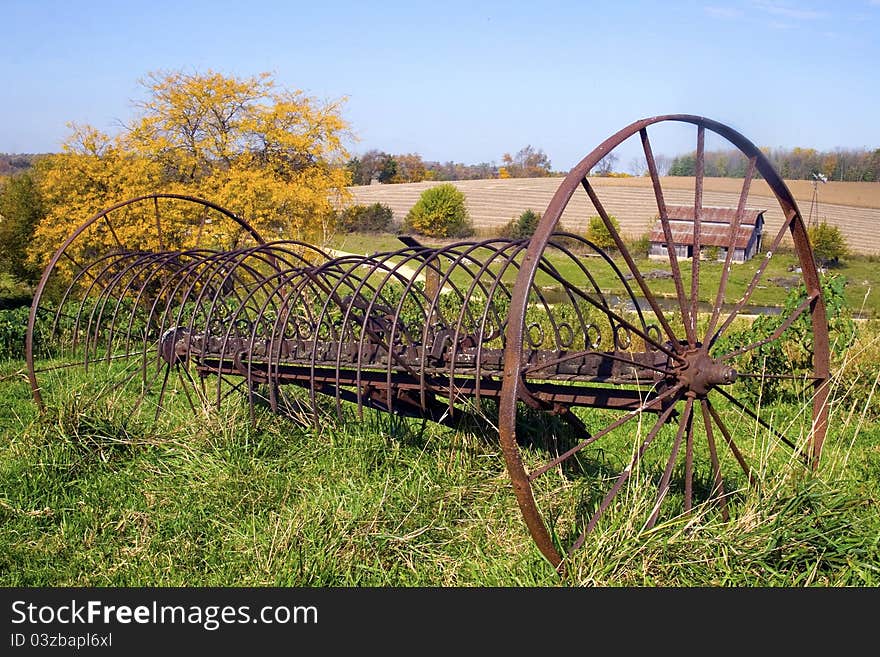 A rustic farm rake sits abandon in a farm pasture. A rustic farm rake sits abandon in a farm pasture.