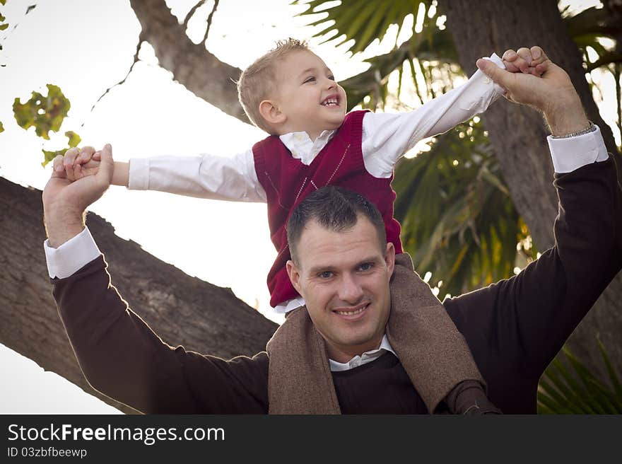 Young Laughing Father and Child Having Piggy Back Fun in the Park. Young Laughing Father and Child Having Piggy Back Fun in the Park.