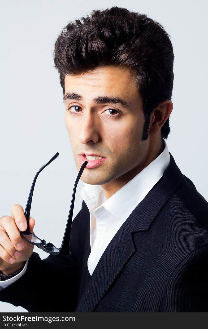 Attractive young businessman looking at the camera with his glasses. Attractive young businessman looking at the camera with his glasses