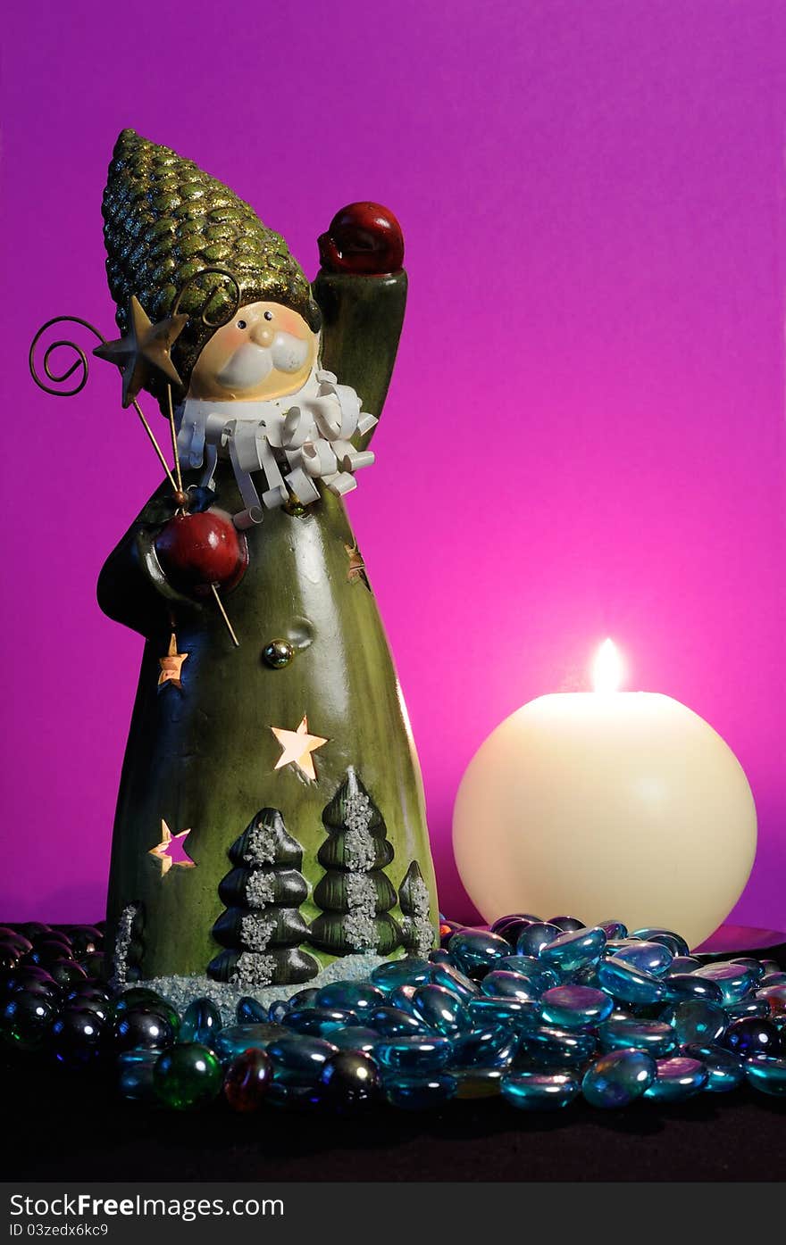 A Santa Claus candlestick and a burning spherical candle with blue glass stones against a magic purple background. A Santa Claus candlestick and a burning spherical candle with blue glass stones against a magic purple background