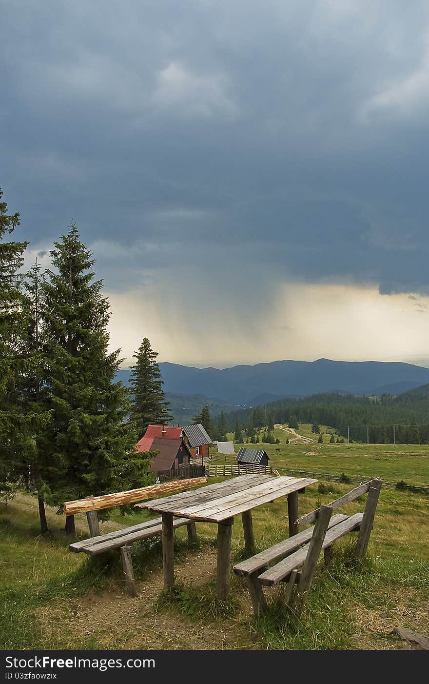 Stormy weather in the mountains in Transylvania with dark sky, wooden bench in front. Stormy weather in the mountains in Transylvania with dark sky, wooden bench in front.