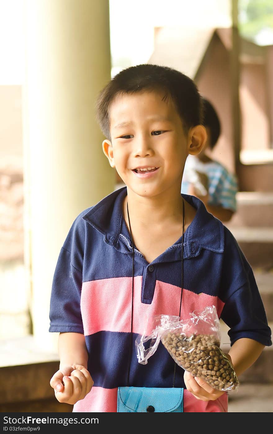 5 Years Asian boy holding fish food to feeding fish in the lake