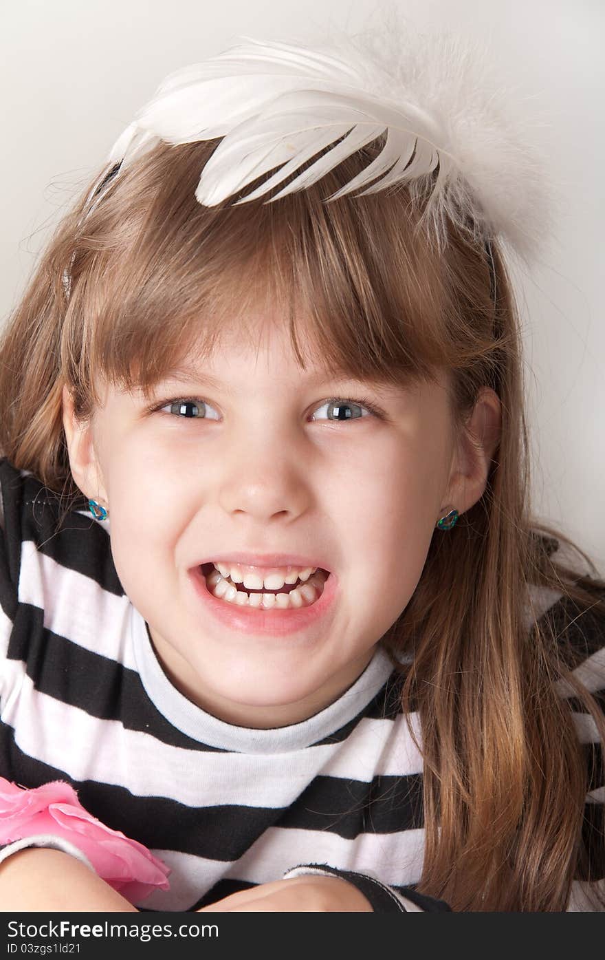 Happy little girl with a white feather on her head