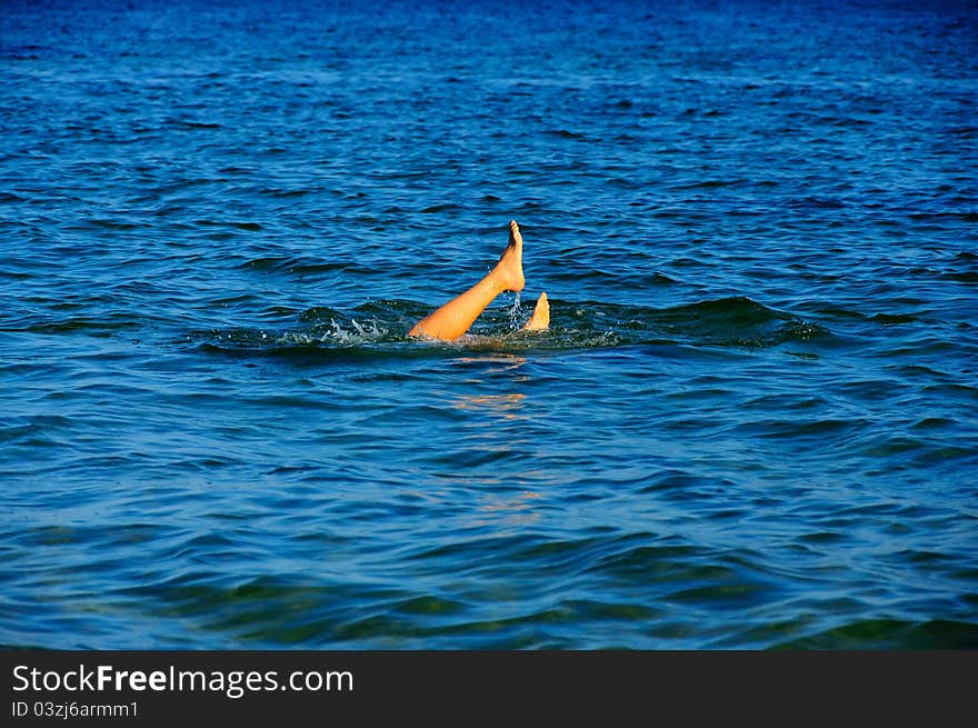 Suntanned legs of the young girl who has dived during time of bathing in the sea. Suntanned legs of the young girl who has dived during time of bathing in the sea