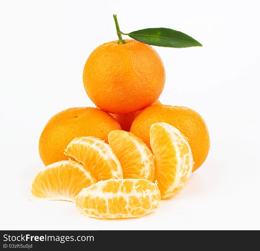 Ripe tangerines with leaves and slices on white background