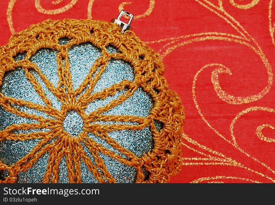 Close-up of a homemade ornament with a snowflake design. Set on a red background with gold glitter swirls. Focus is on the ornament. Close-up of a homemade ornament with a snowflake design. Set on a red background with gold glitter swirls. Focus is on the ornament.