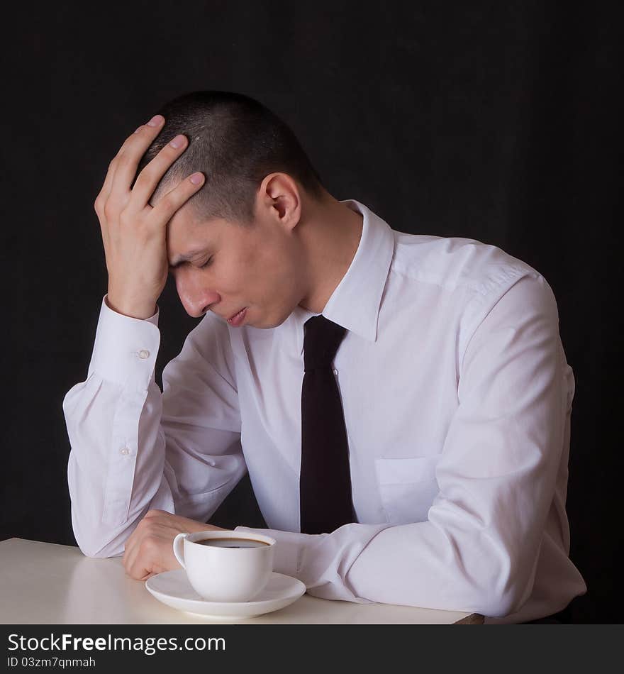 Upset businessman drinking coffee