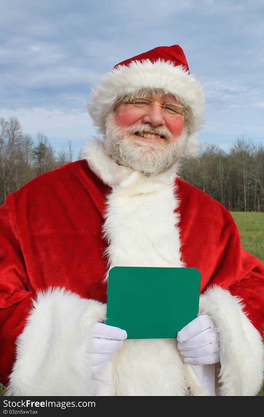 Santa Claus in an outdoor setting holding a chalk board in his gloved hands. Write your own message. Santa Claus in an outdoor setting holding a chalk board in his gloved hands. Write your own message.