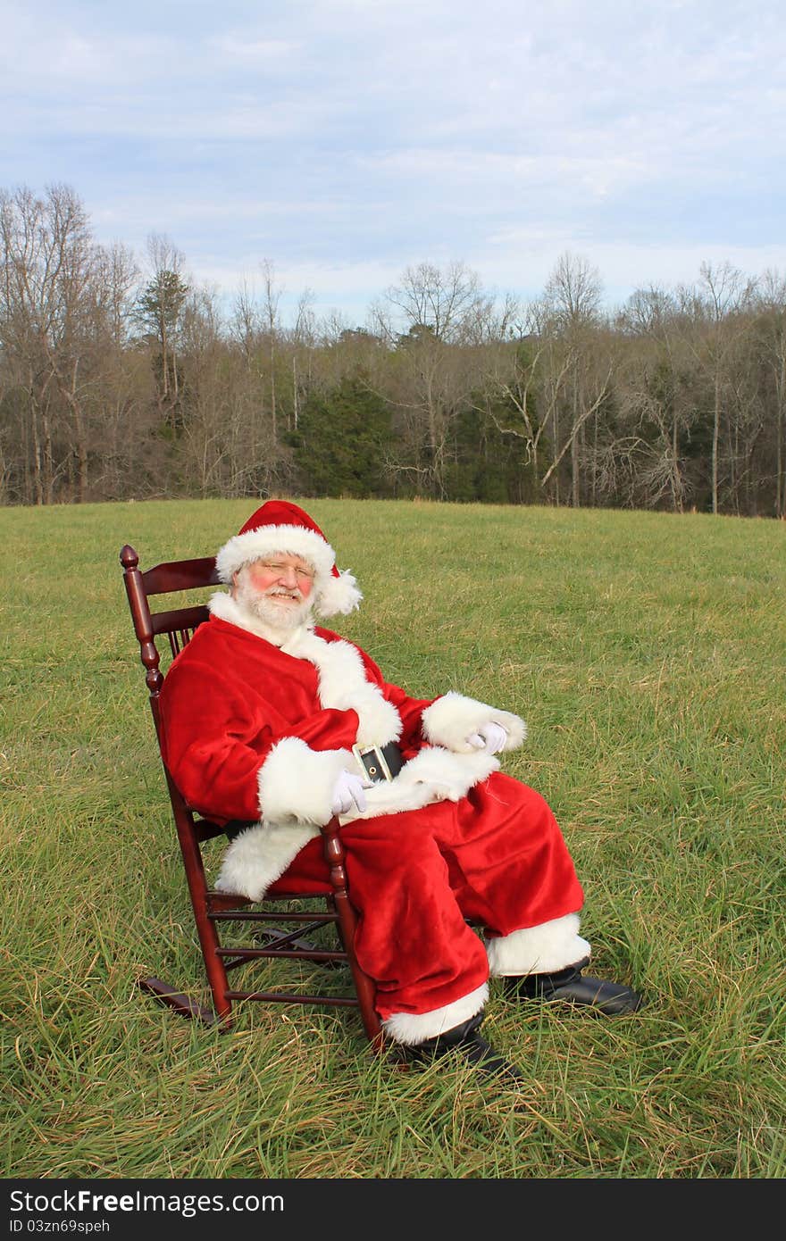 Santa Claus sitting in a rocking chair in an open field. Santa Claus sitting in a rocking chair in an open field.