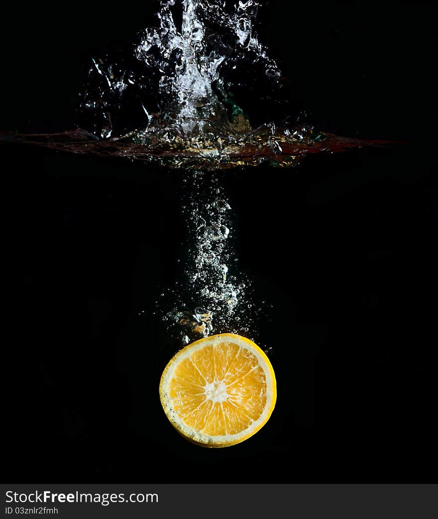 Orange falling in water, splashes against a dark background. Orange falling in water, splashes against a dark background