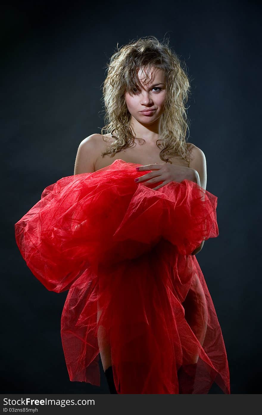 Portrait of naked pretty girl cover up in red nylon on a dark background in studio. Portrait of naked pretty girl cover up in red nylon on a dark background in studio