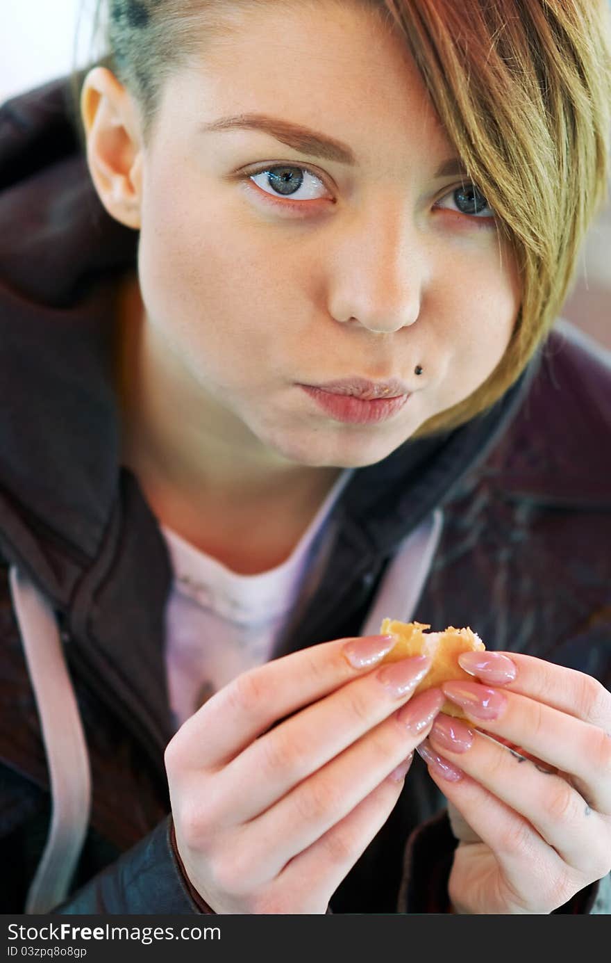 Portrait of stylish blond girl with eats burger on the terrace of the fast food. Portrait of stylish blond girl with eats burger on the terrace of the fast food