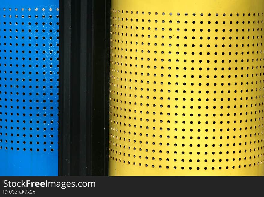 The close-up of a colorized wastebin with many small circular holes