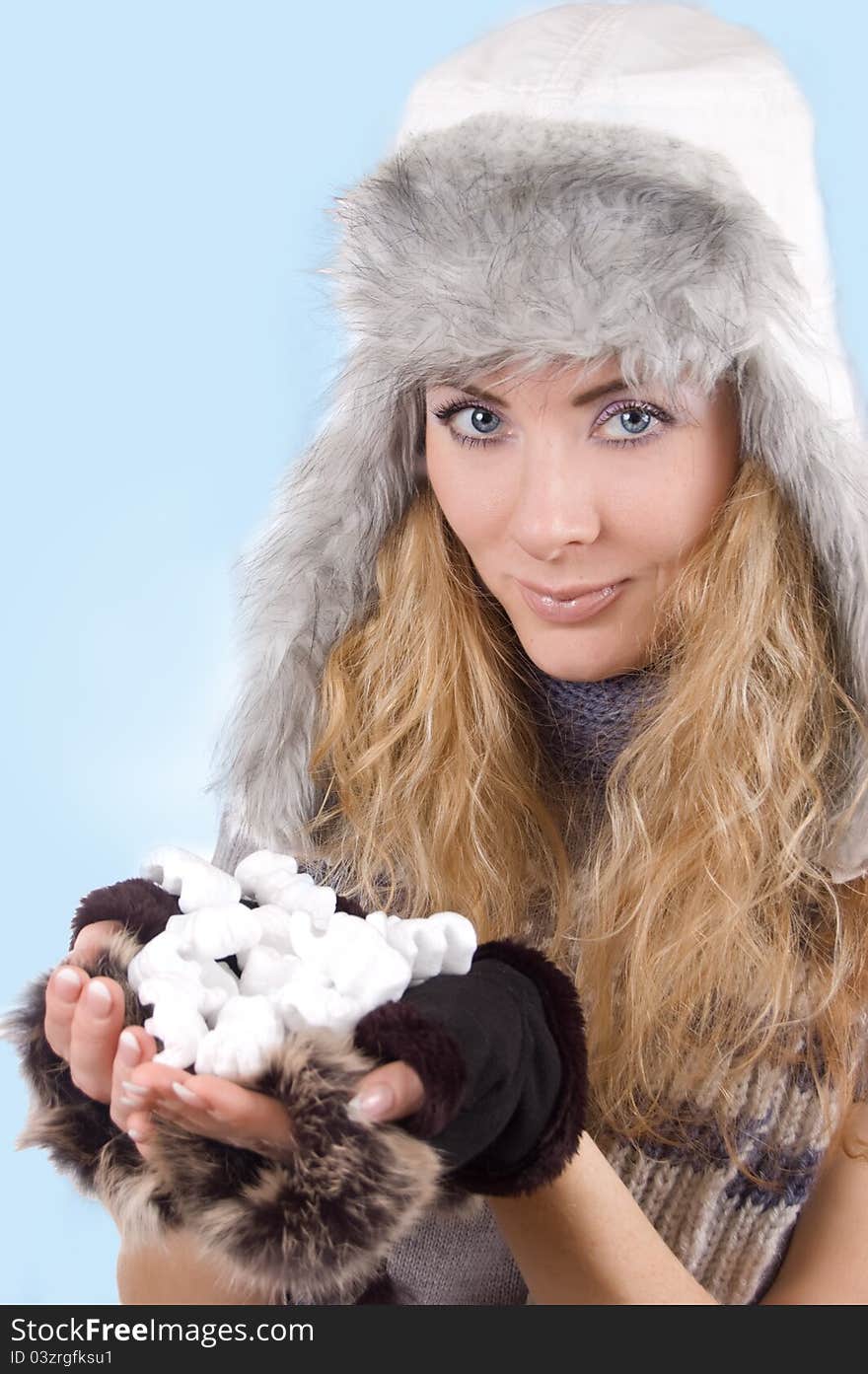 Woman in winter hat and gloves with snow over blue back