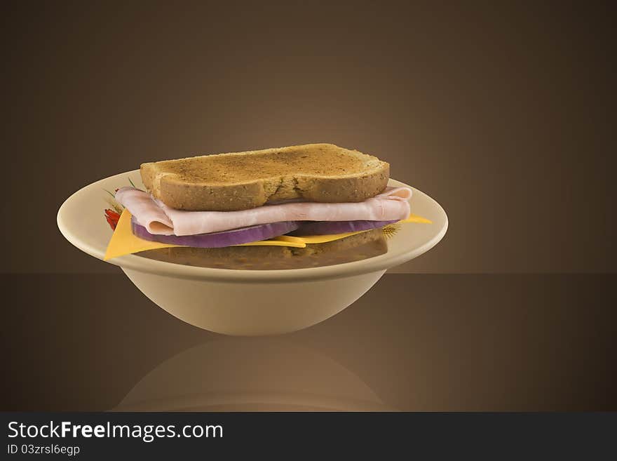 Bowl of soup with a ham and cheese sandwich partly submerged in the soup. Bowl of soup with a ham and cheese sandwich partly submerged in the soup.