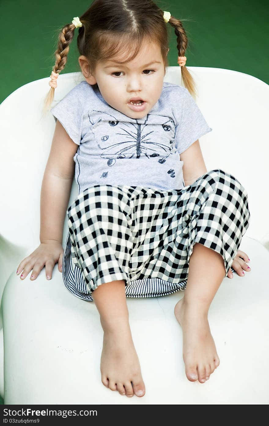 Cute little girl sitting on the white chair. Cute little girl sitting on the white chair