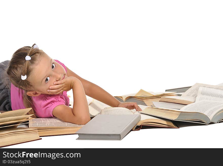 Nice little barefooted girl lying on the pile of open of books and smiling isolated on white background