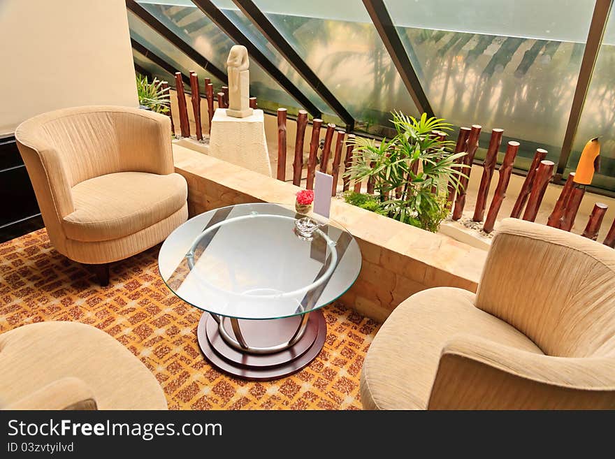 Armchairs and glass table inside a hotel Lobby.