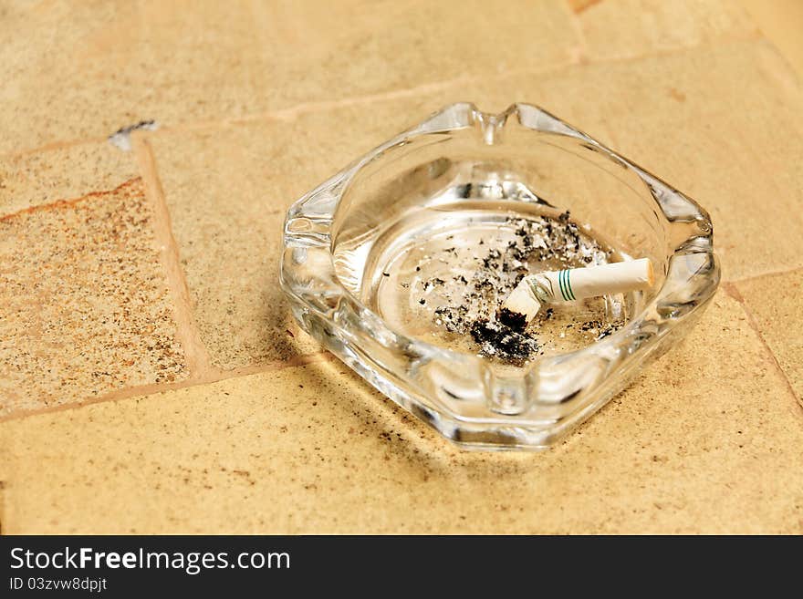 Cigarette butt in a glass ashtray. Cigarette butt in a glass ashtray.