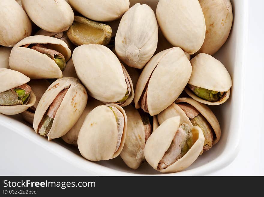 Close-up roasted and salted pistachios on white plate