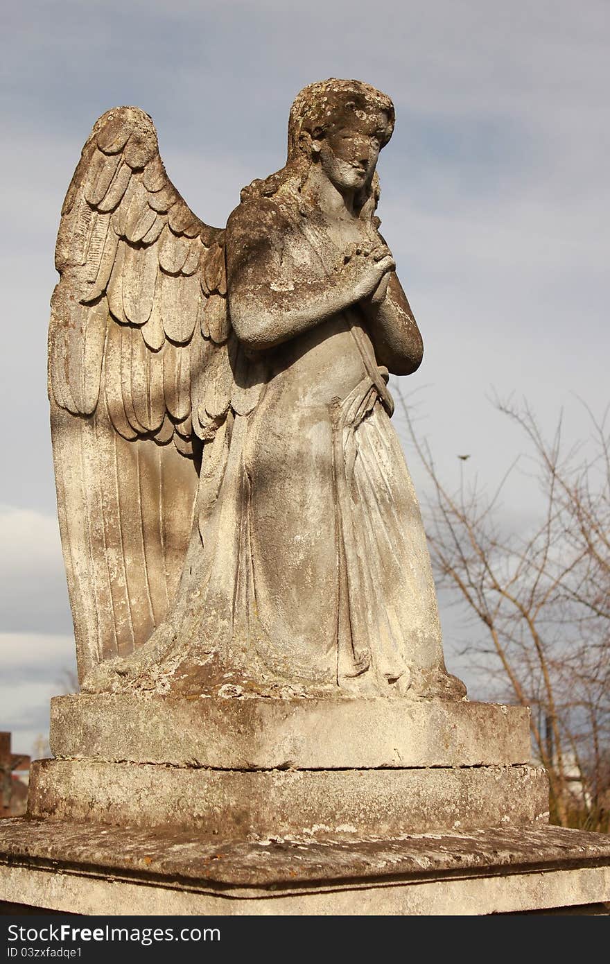 Figure of a praying angel on a blue sky