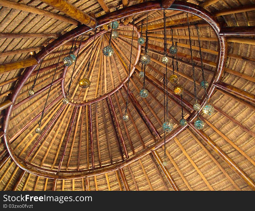 The indoor section of a palapa roof decorated with glass balls hanging on string.