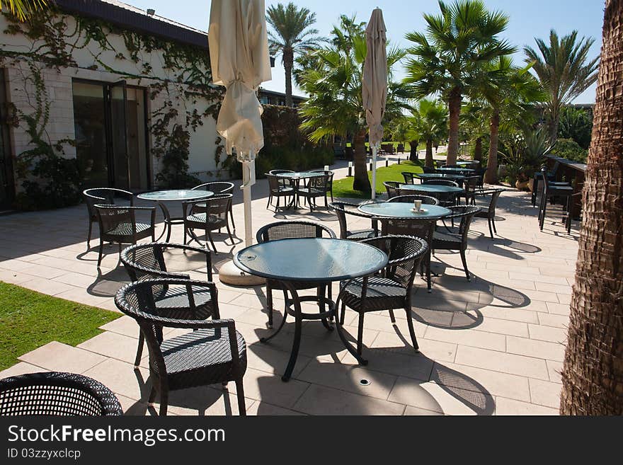 Outdoors cozy Cafe in a Mediterranean resort hotel with palm trees around. Outdoors cozy Cafe in a Mediterranean resort hotel with palm trees around