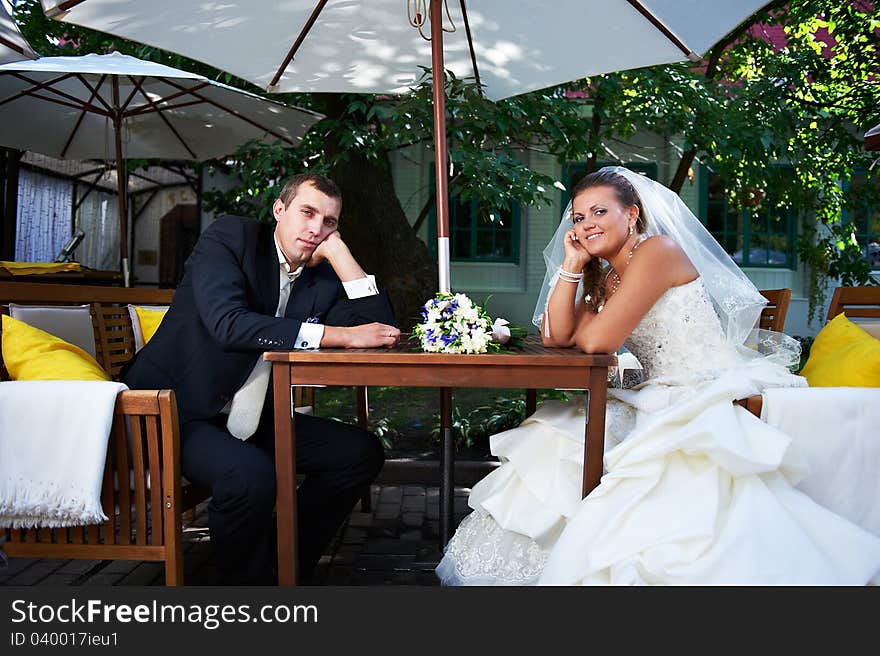 Bridal couple sitting on the benches in the cafe. Bridal couple sitting on the benches in the cafe