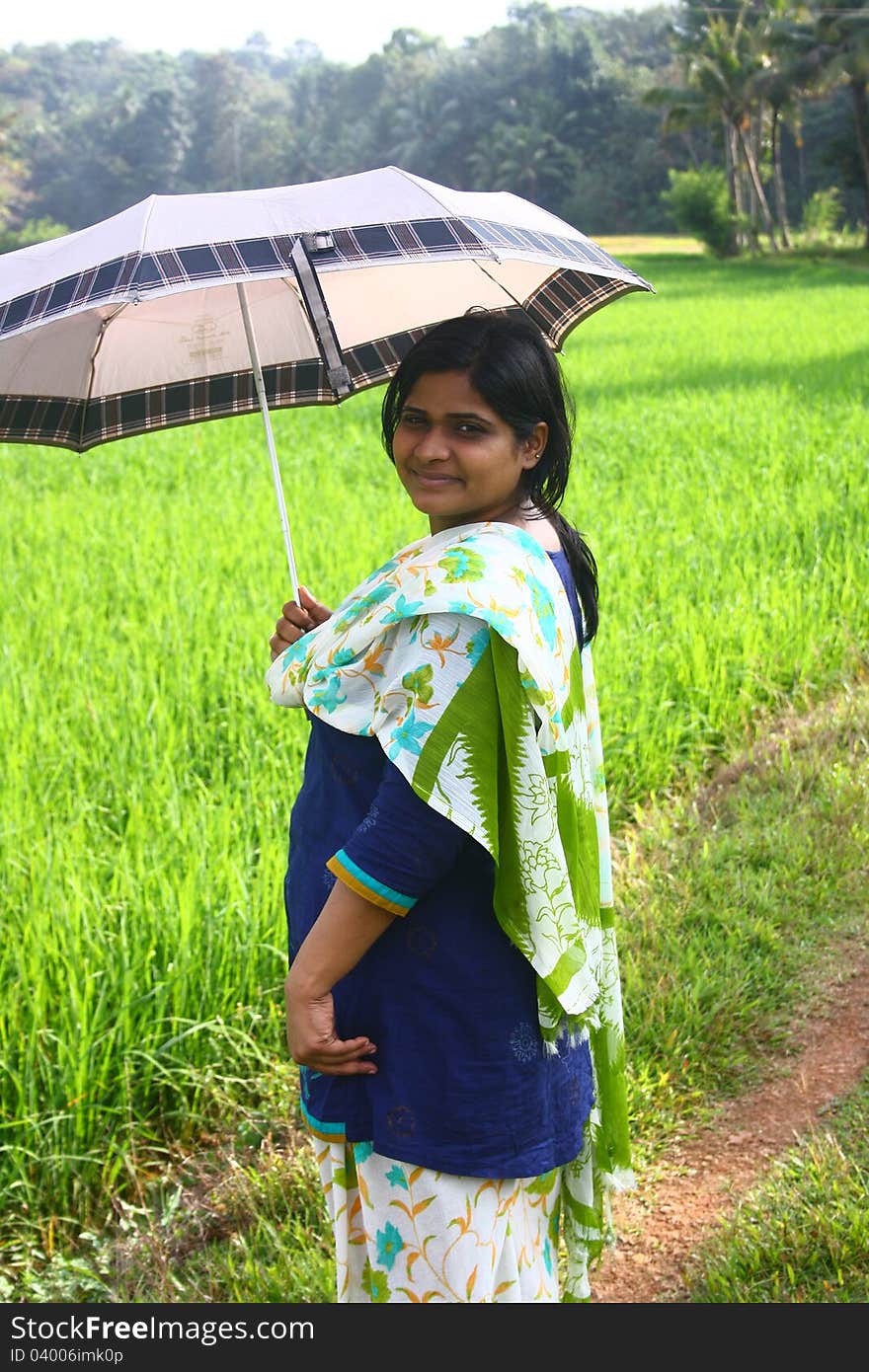 Indian Village Girl Holding Umbrella in the morning Sunlight with a beautiful paddy field as background. Indian Village Girl Holding Umbrella in the morning Sunlight with a beautiful paddy field as background