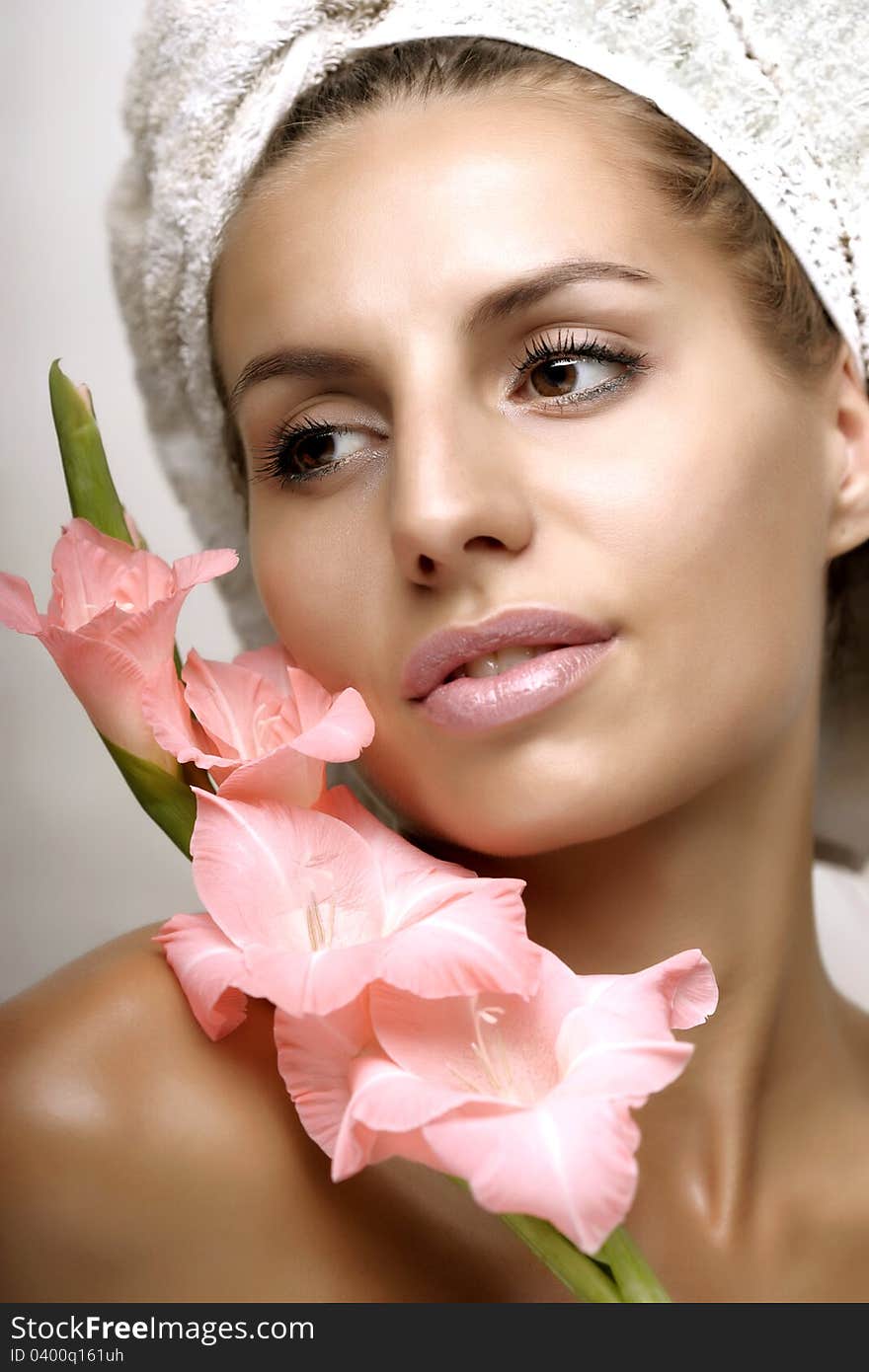 Closeup portrait of a pretty young woman with flower and towel