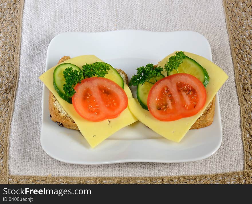 Devided bun sandwiches with cheese and vegetables on a plate. Devided bun sandwiches with cheese and vegetables on a plate