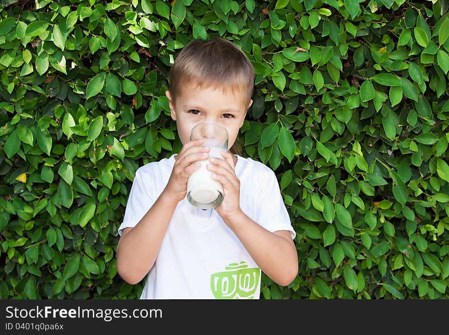 Cute boy drinking milk from a transparent glass