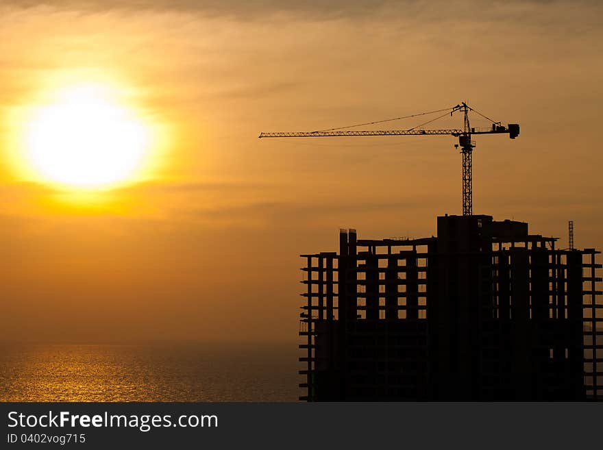 Industrial construction cranes and building silhouettes with sunset