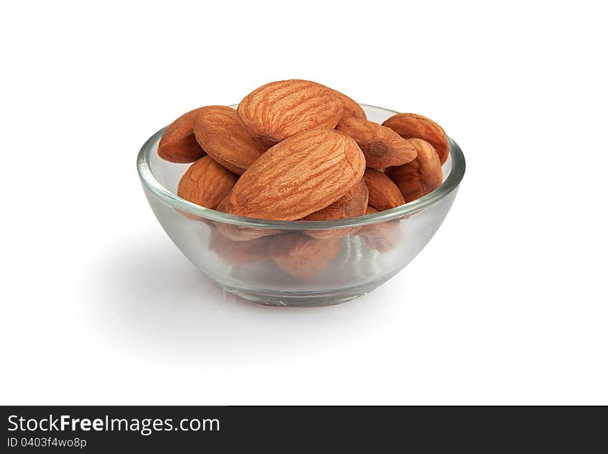 Pile of  almonds in transparent glass small bowl isolated over white background