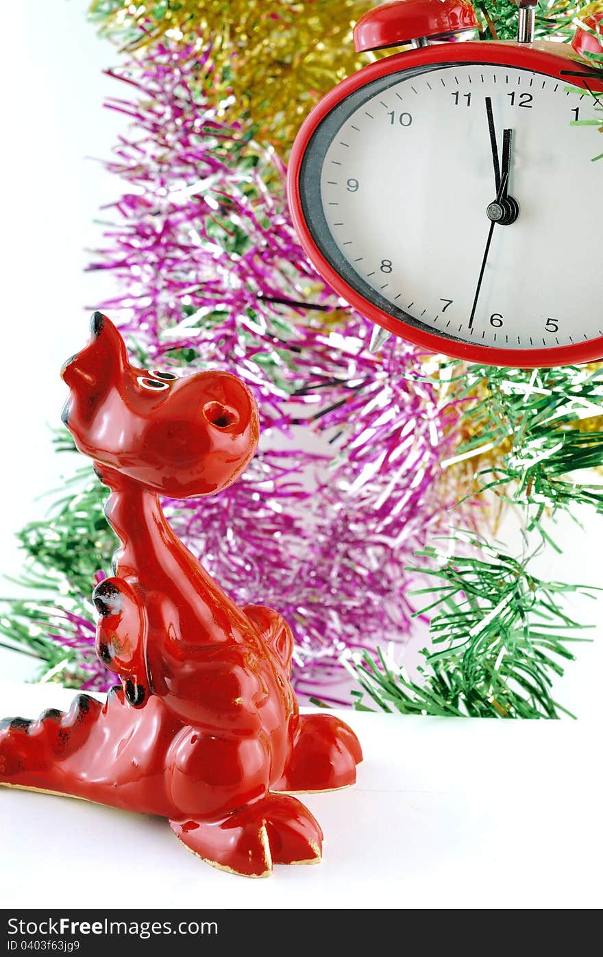 Small decorative dragon looks at the clock on that soon will ring at midnight. Small decorative dragon looks at the clock on that soon will ring at midnight