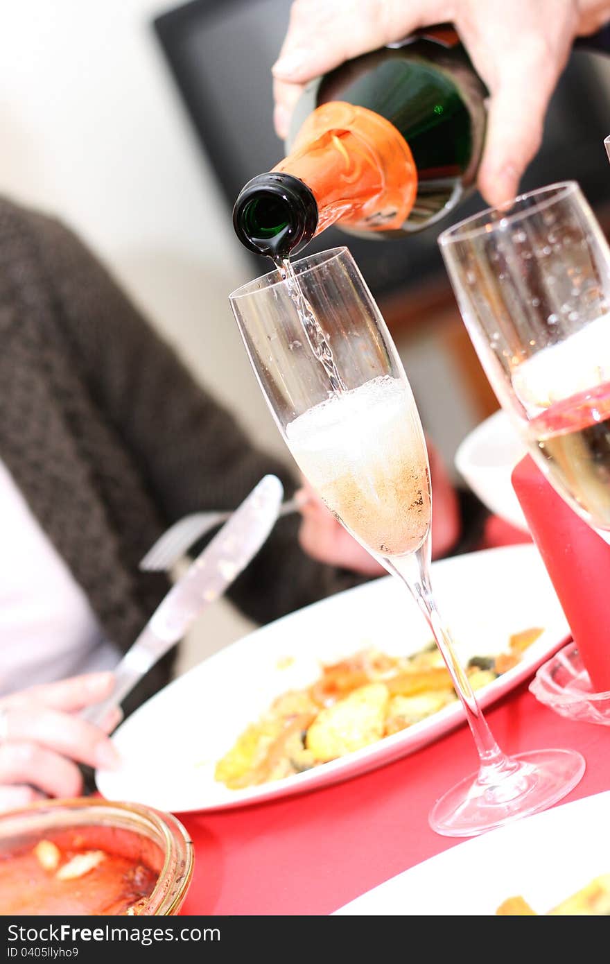 Hand with bottle pouring champagne into a glass