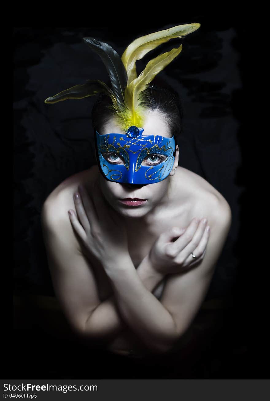 Girl in carnival mask with feathers on a dark background. Girl in carnival mask with feathers on a dark background