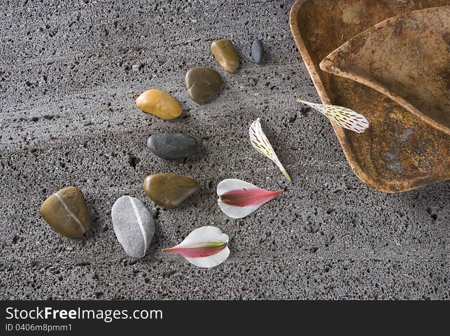 Stones, petals and recipient on a textured stone. Stones, petals and recipient on a textured stone