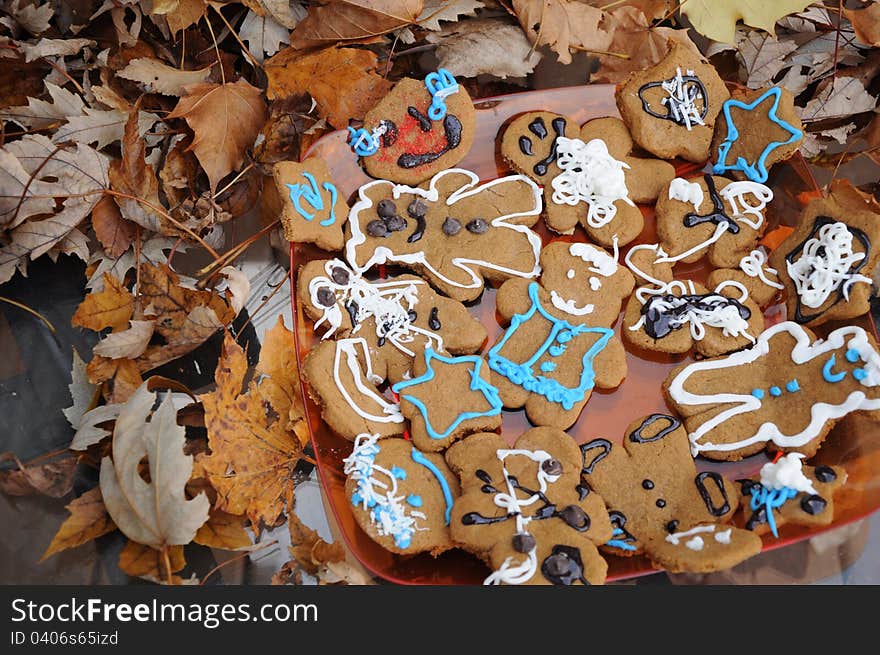 A platter of homemade gingerbread cookies next to a pile of fall leaves.