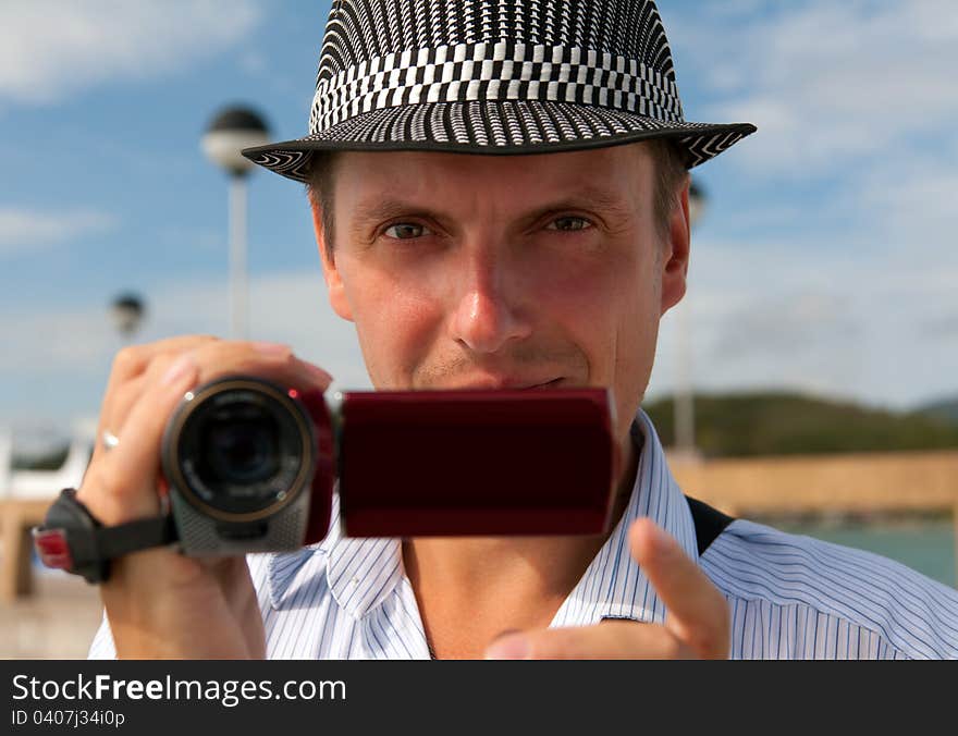 Man in a hat with a camera looking to the frame