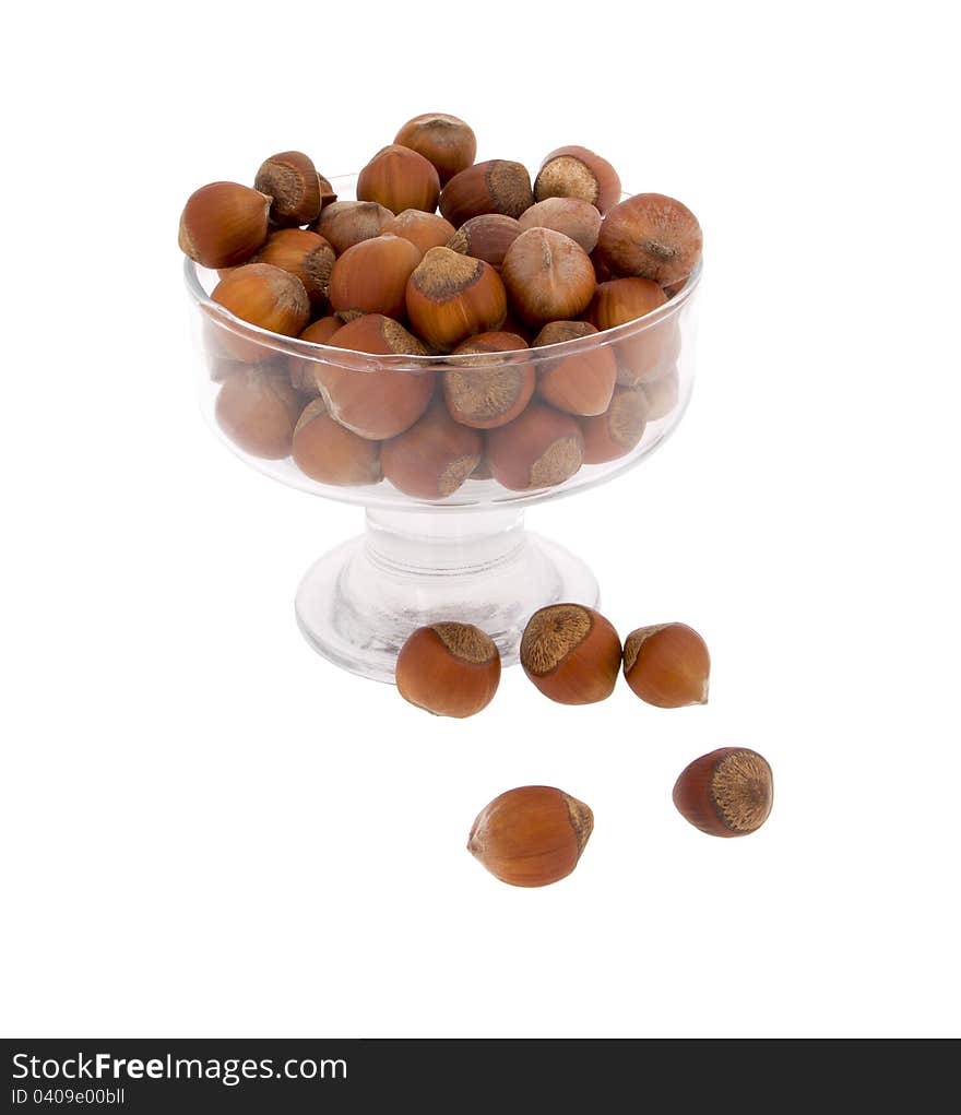 Hazelnuts in a glass vase on a matter of background