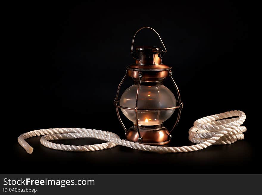 Old lamp and rope on black background